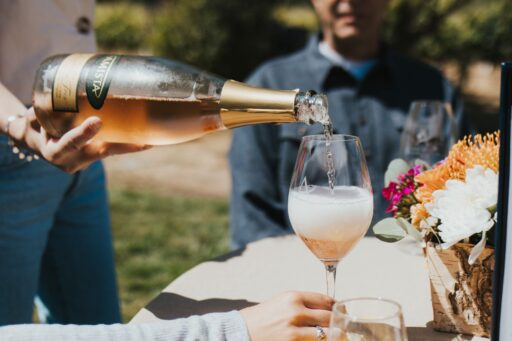 Amista Sparkling Rose Wine Being Poured into a Glass at a table outside