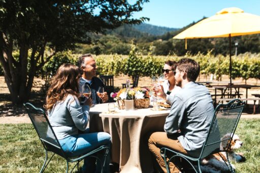 Two Men Two Women and a Dog sitting at a table in at Amista Vineyards tasting wine